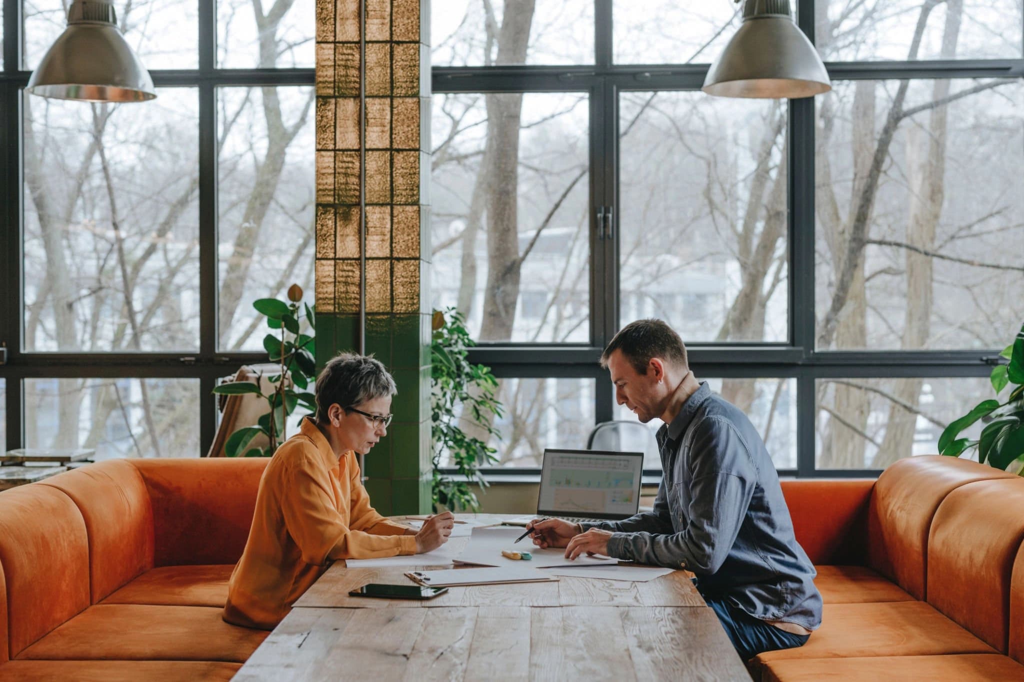 Two people collaborating at a table by a large window.