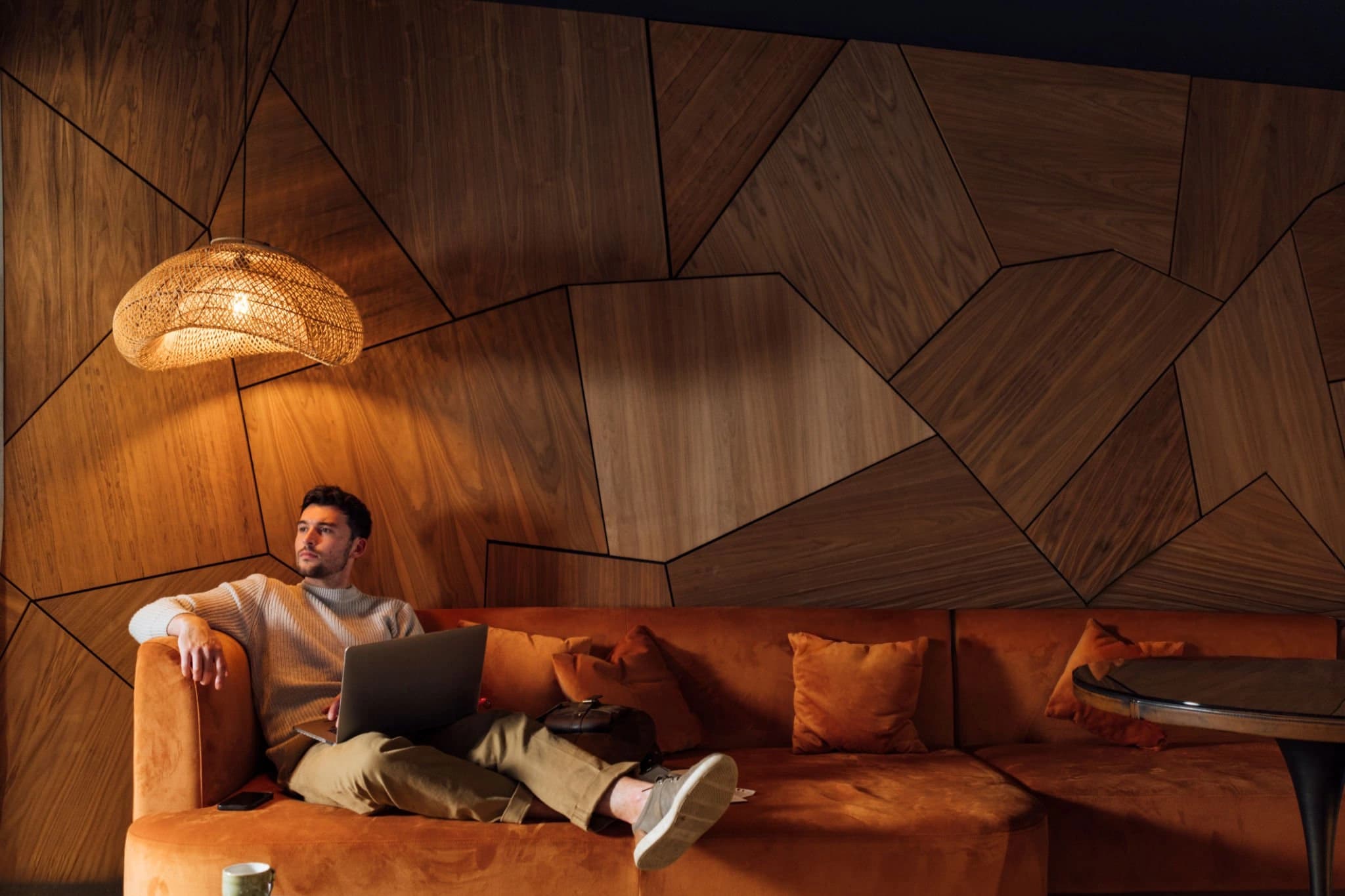 Person working on a laptop in a warm wood-paneled lounge.