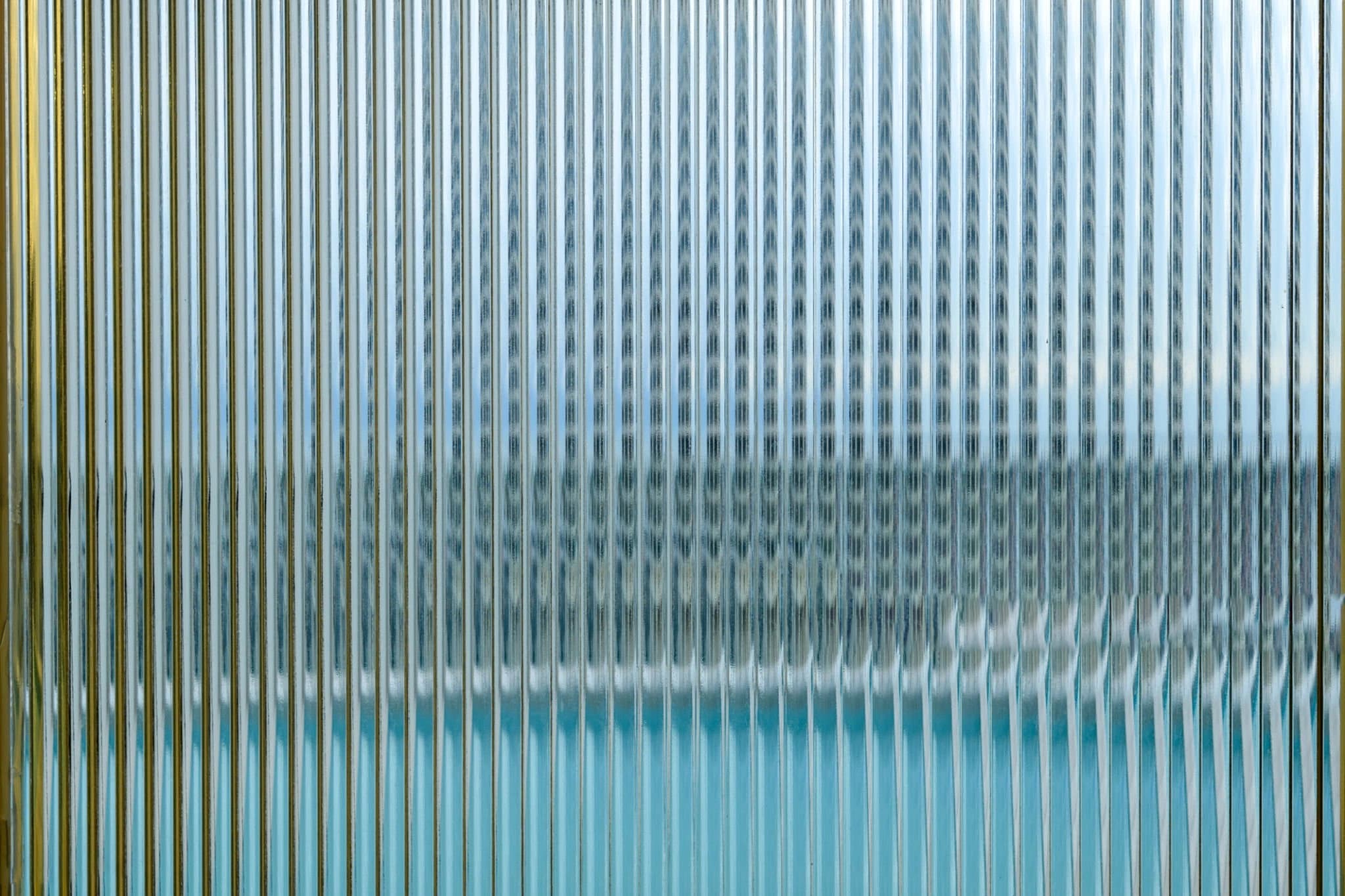 Blue and green water seen through ribbed glass.